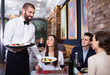 © JackF - Waiter with dishes serving man and woman friendly company indoors