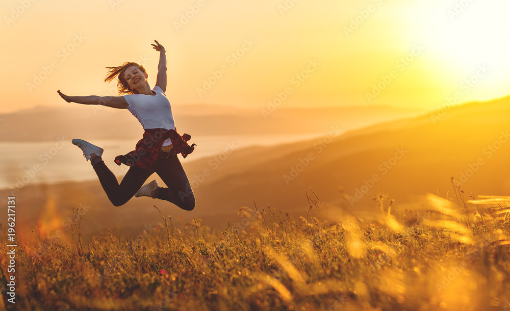 Happy woman jumping and enjoying life  at sunset in mountains. - obrazy, fototapety, plakaty 