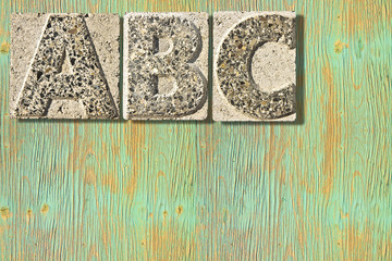 Fototapete - Letter A-B-C carved in a concrete block over a wooden background - concept image with copy space