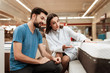 © freeograph - Lovely woman consultant demonstrates orthopedic mattress to confident man in furniture store.