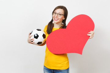 Wall Mural - Smiling European woman, fun pony tails, football fan or player in glasses, yellow uniform hold classic soccer ball, red heart isolated on white background. Sport, football, healthy lifestyle concept.