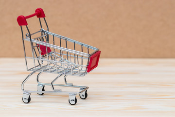 Shopping cart on wooden surface. Symbol of consumerism