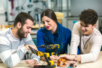 Young students of robotics preparing robot for testing in workshop