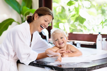mother washing baby in bubble bath. water fun.