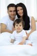 © ASDF - Happy couple and son sitting in bed