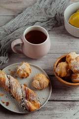 Wall Mural - Delicious homemade cakes and desserts. Cream profitroles with sugar powder on plate on white wooden background