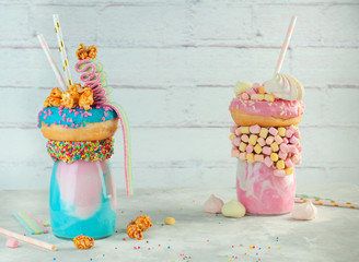 Wall Mural - Two freak shakes topping with donut, popcorn and marmalade over brick background