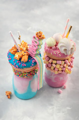 Wall Mural - Two freak shakes topping with pink and blue donuts over grey background