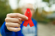 red aids ribbon in hand on green background, HIV