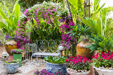 Flowers and comfortable lounge chair  in the spring garden. Beautiful small garden.