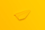 Yellow origami plane on a yellow background. View from above.