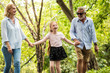 © ronnarong - Happy family having fun together in the garden. Father, mother and daughter holding hands and walking in a park. Lifestyle concept