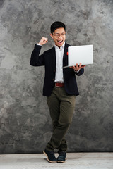 Wall Mural - Full length portrait of an excited young asian man