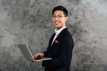 Wall Mural - Portrait of a smiling young asian man dressed in suit