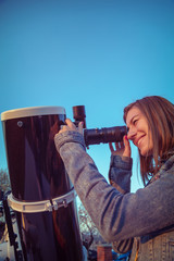Wall Mural - cute young woman holding astronomical telescope and looking at the sky.