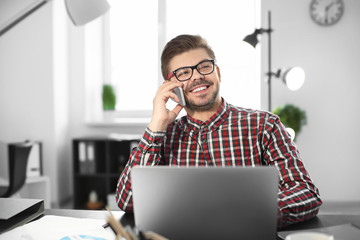 Canvas Print - Young man talking on phone while working in office