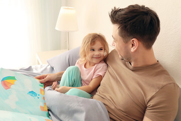 Wall Mural - Father with little daughter reading bedtime story at home