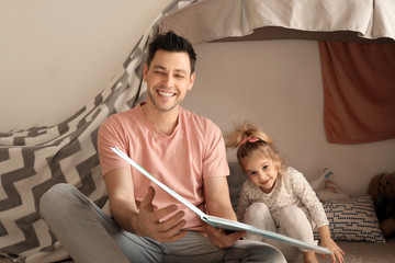 Wall Mural - Father with little daughter reading bedtime story near hovel at home