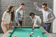 © Bojan - Cheerful business people playing billiards during office break.