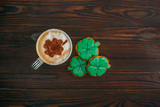 Fototapeta Zwierzęta - top view of cappuccino and cookies in shape of shamrocks on wooden table