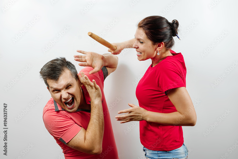 Family quarrel, wife scolds her husband, young, beautiful wife beats her husband with a stick. The concept of the psychology of family relations, marriage, domestic conflicts, domestic violence. Stock-bilde | Adobe Stock