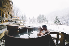 Couple Sitting In Plunge Tub In Winter