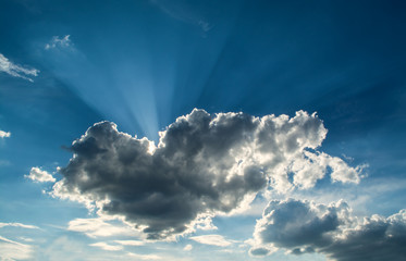 Wall Mural - sun rays against a blue sky in the clouds