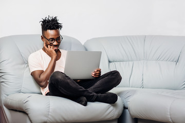 Wall Mural - man in glasses sitting with laptop on sofa