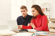 © Prostock-studio - Male and female students at wooden table full of books