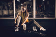 © Dusan Petkovic - Front view of a satisfied fitness sporty young girl sitting on the gym floor and tying shoelaces.