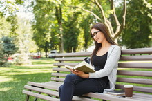 Young Woman Reading Book In Park Copy Space