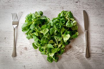 fresh lettuce leaves, salad on a plate placed on a wooden table