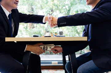 corrupted two businessman sealing the deal with a handshake and receiving a bribe money. hands passi