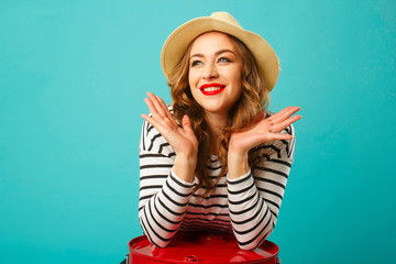 Wall Mural - Portrait of young beautiful blond woman in hat with happy expression on her face over blue background