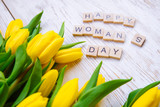 Fototapeta Tulipany - happy woman's day text. tulips overhead on white wooden background