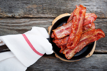 Hot fried bacon pieces in a cast iron skillet.top view