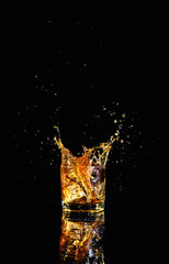 Isolated shot of whiskey with splash on black background, brandy in a glass