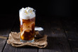 Iced coffee in a tall glass with cream poured over.
