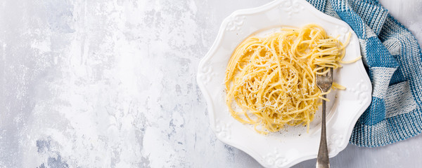 Wall Mural - Cacio e Pepe - pasta spaghetti with pecorino cheese and pepper. Healthy italian traditional food concept with copy space. Overhead shot, top view. Banner.