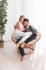 Poster - Cute young lovely couple sitting in armchair at home