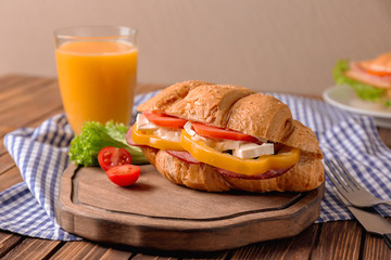 Wall Mural - Tasty croissant sandwich and glass of juice served for breakfast on table