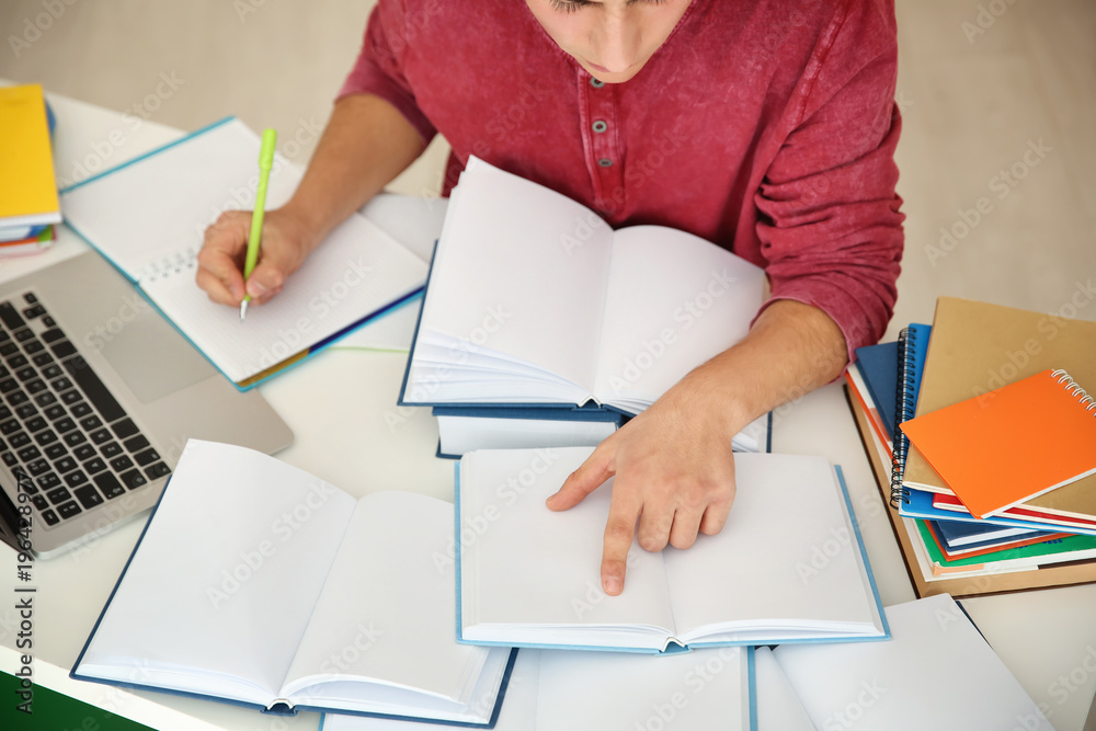 Male student preparing for exam at table