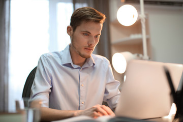 Canvas Print - Young man working with laptop indoors