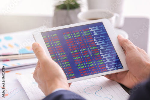 человек с планшетом управляет финансами, видны диаграммы