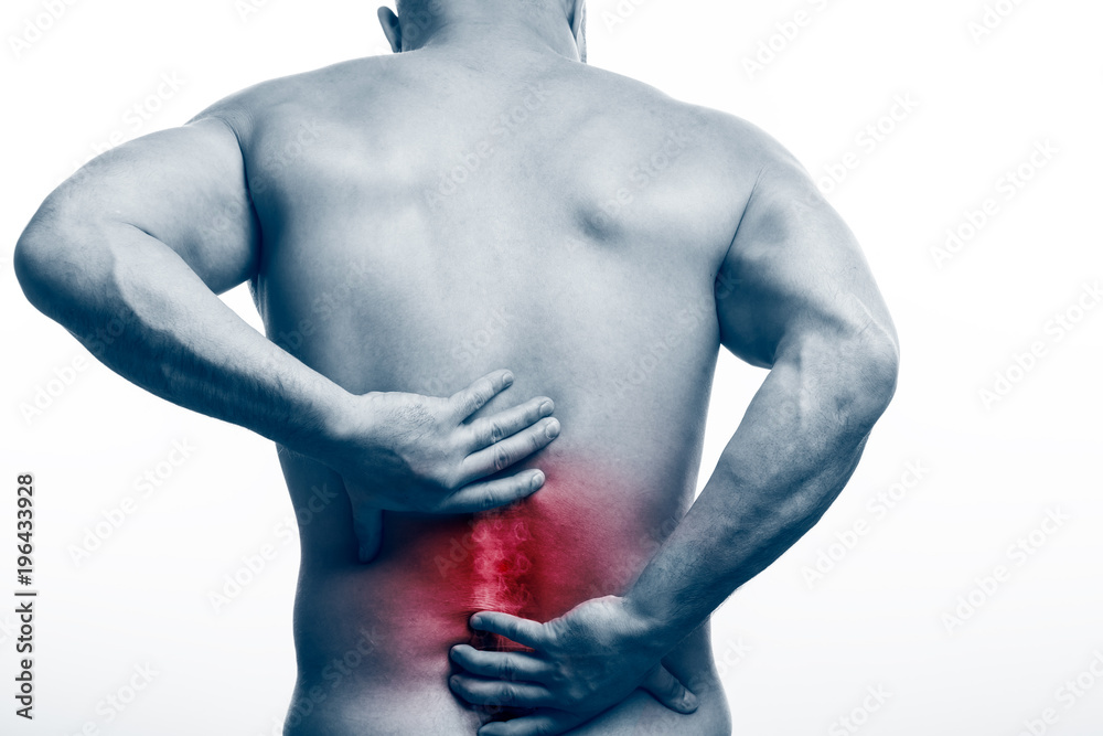 Injury of the spine. Young bald man sports physique holds a sick back ...