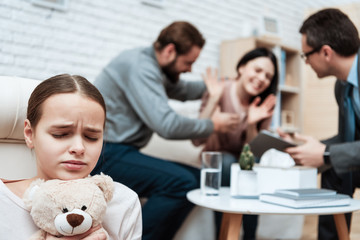 Wall Mural - Frightenedgirl with teddy bear in hands avoids scandal of parents in psychiatrist's office.