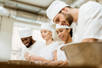 group of happy baking manufacture workers kneading dough together