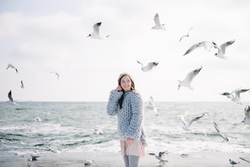 Wall Mural - happy young girl in merino sweater on winter seashore with seagulls