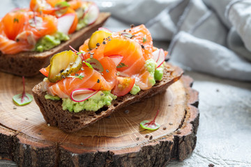 Smorrebrod with salmon on rye bread with vegetables and herbs