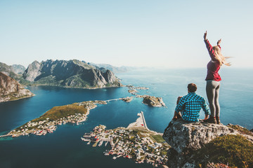 Wall Mural - Couple travelers traveling together on top cliff Reinebringen mountain in Norway man and woman family lifestyle concept summer vacations outdoor aerial view Lofoten islands
